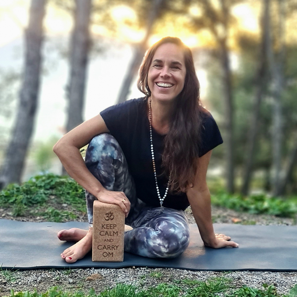 Julia Giaccone sitzt auf der Matte mit der Sonne hinter sich und lächelt zu Camera