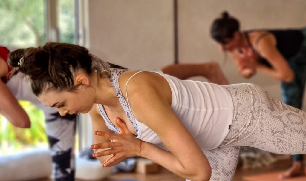 Participants of a yoga class perform warrior 3 pose