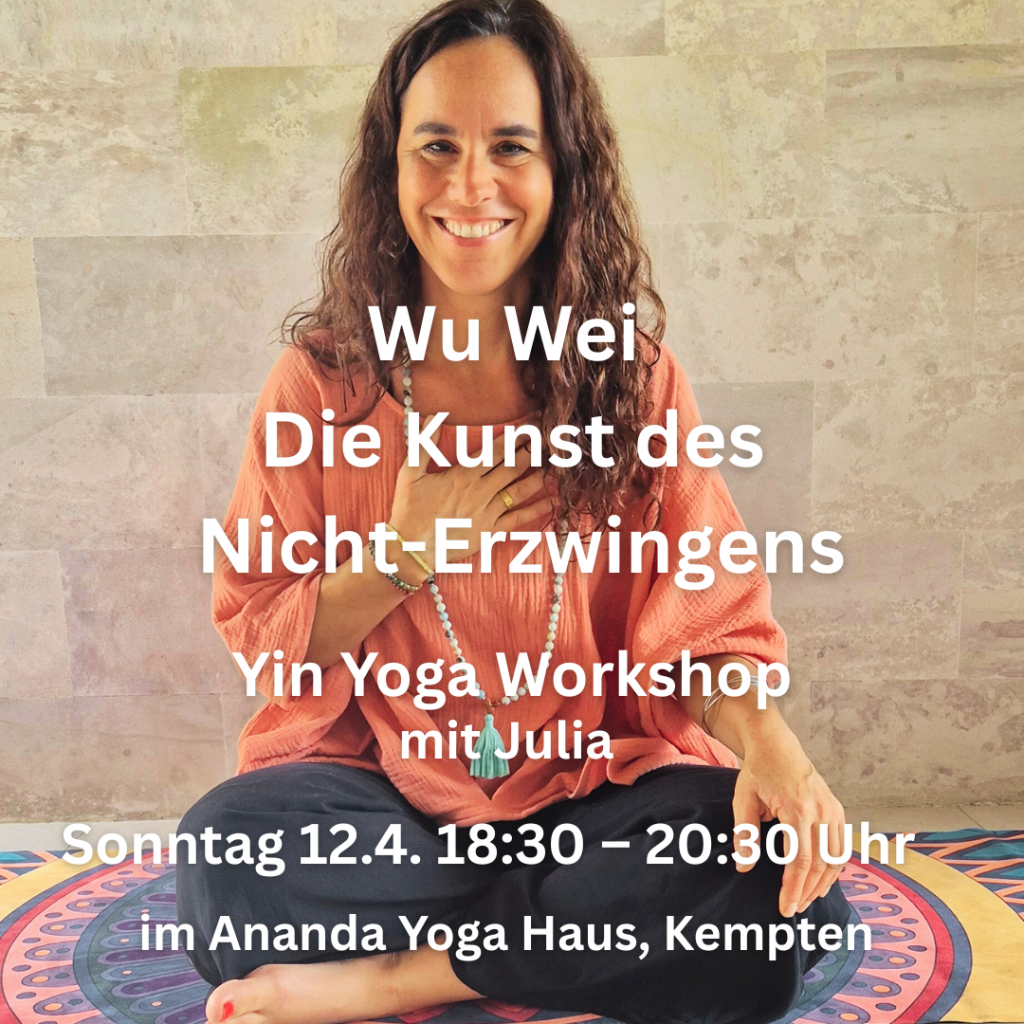 Julia sitzt im Schneidersitz und lächelt zum Camera mit einer Hand am Herz